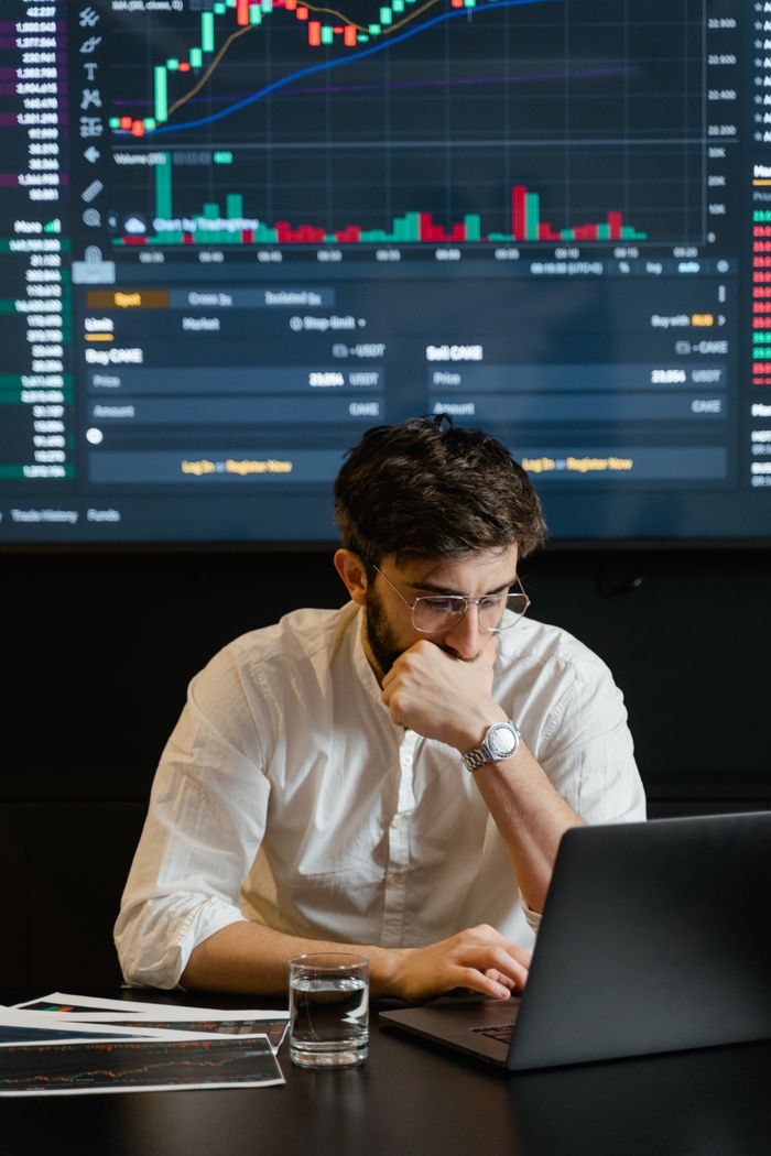 Businessman analyzing stock market data on laptop with graphs displayed. Focused and thoughtful.